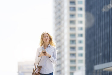 Blonde Frau mit Handtasche und Mobiltelefon geht durch die Stadt - SBOF01617