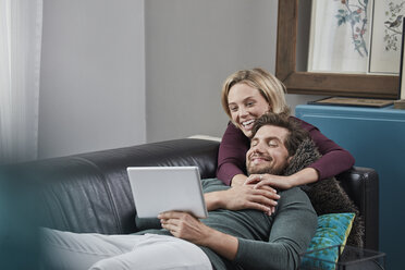 Glückliches Paar mit Tablet auf der Couch zu Hause - RORF01570