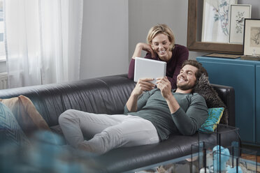 Happy couple with tablet on couch at home - RORF01577