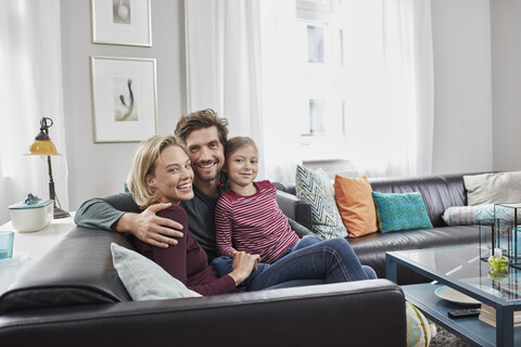 Porträt einer glücklichen Familie, die zu Hause auf der Couch sitzt, lizenzfreies Stockfoto