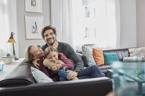 Porträt einer glücklichen Familie, die zu Hause auf der Couch sitzt, lizenzfreies Stockfoto