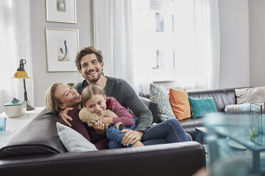 Porträt einer glücklichen Familie, die zu Hause auf der Couch sitzt - RORF01587