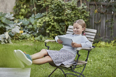 Lächelndes Mädchen benutzt Tablet im Garten - RORF01596