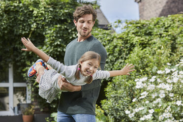 Glücklicher Vater spielt mit seiner Tochter im Garten ihres Hauses - RORF01598