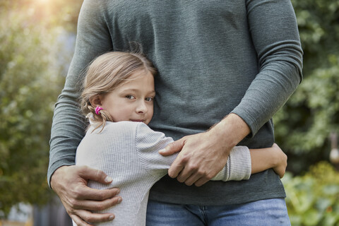Porträt eines Mädchens, das seinen Vater im Garten umarmt, lizenzfreies Stockfoto