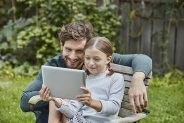 Glücklicher Vater und Tochter benutzen gemeinsam ein Tablet im Garten - RORF01609