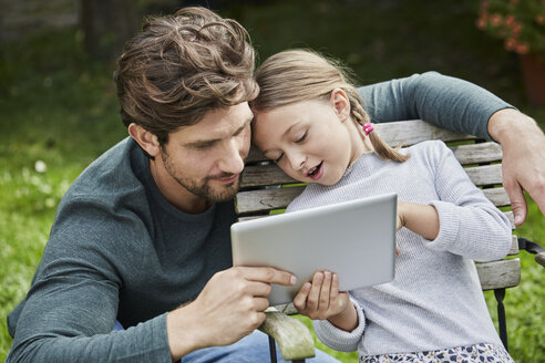 Vater und Tochter benutzen gemeinsam ein Tablet im Garten - RORF01611