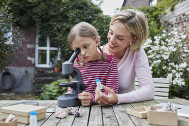 Mutter und Tochter benutzen gemeinsam ein Mikroskop am Gartentisch - RORF01613