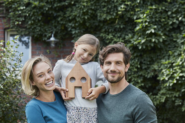 Porträt einer glücklichen Familie vor ihrem Haus mit Hausmodell - RORF01622