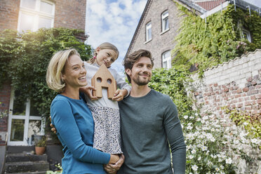 Porträt einer glücklichen Familie vor ihrem Haus mit Hausmodell - RORF01623
