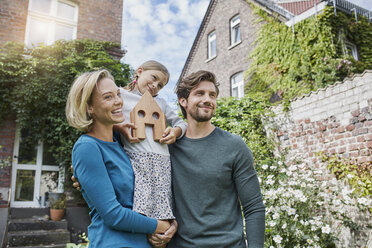 Portrait of happy family in front of their home with house model - RORF01623