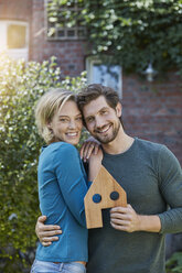 Portrait of happy couple in front of their home with house model - RORF01627