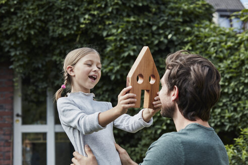 Father and daughter in garden of their home with house model - RORF01629