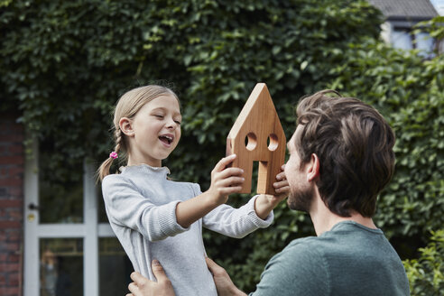 Vater und Tochter im Garten ihres Hauses mit Hausmodell - RORF01629