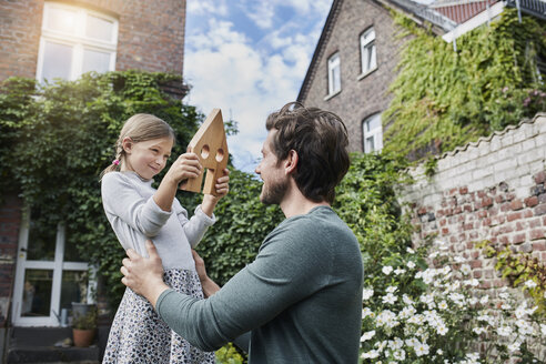 Father and daughter in garden of their home with house model - RORF01630
