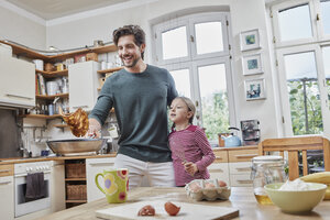 Glücklicher Vater und Tochter backen gemeinsam Pfannkuchen in der Küche zu Hause - RORF01631