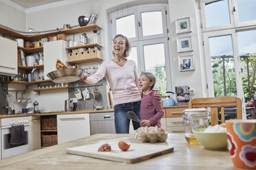 Glückliche Mutter und Tochter backen Pfannkuchen in der Küche zu Hause zusammen - RORF01632