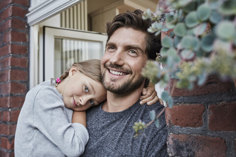 Lächelnder Vater mit Tochter am Hauseingang ihres Wohnhauses, lizenzfreies Stockfoto