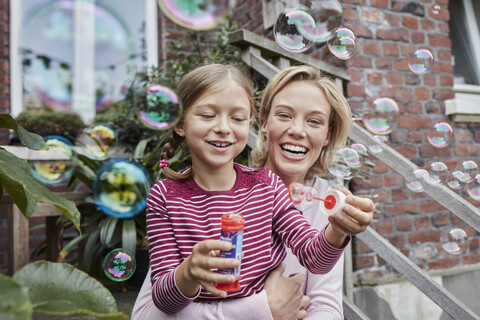 Happy mother and daughter making soap bubbles stock photo
