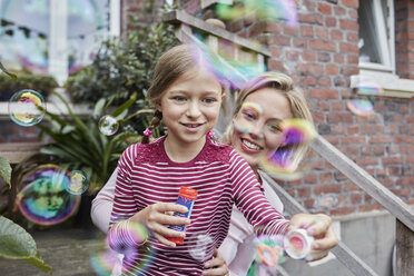 Happy mother and daughter making soap bubbles - RORF01652