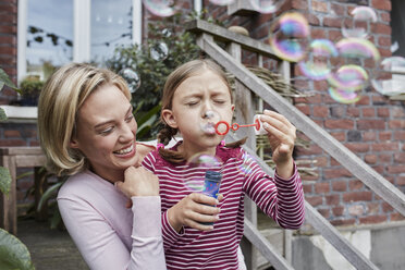 Happy mother and daughter making soap bubbles - RORF01653