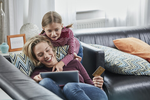 Glückliche Mutter und Tochter beim Online-Shopping auf der Couch zu Hause, lizenzfreies Stockfoto