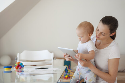 Mutter und kleine Tochter benutzen gemeinsam ein Tablet zu Hause, lizenzfreies Stockfoto