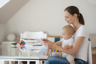 Mutter und kleine Tochter benutzen gemeinsam ein Tablet zu Hause - DIGF05630