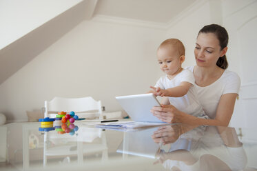 Mutter und kleine Tochter benutzen gemeinsam ein Tablet zu Hause - DIGF05631