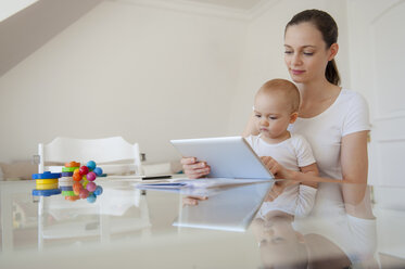 Mutter und kleine Tochter benutzen gemeinsam ein Tablet zu Hause - DIGF05632
