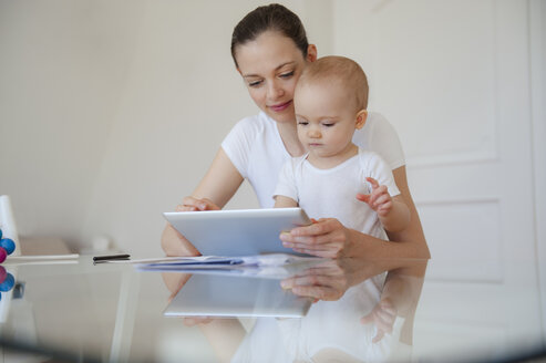 Mutter und kleine Tochter benutzen gemeinsam ein Tablet zu Hause - DIGF05633