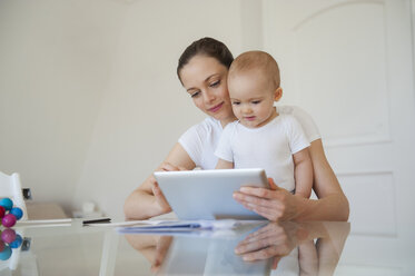 Mutter und kleine Tochter benutzen gemeinsam ein Tablet zu Hause - DIGF05634