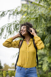 Glückliche Frau hört Musik mit Kopfhörern im Freien - MAUF02346