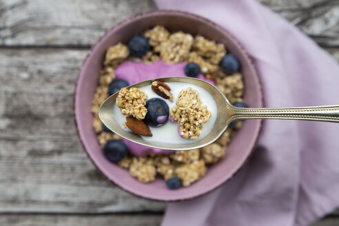 Granola, almonds, blueberry and milk on spoon, close-up - LVF07666