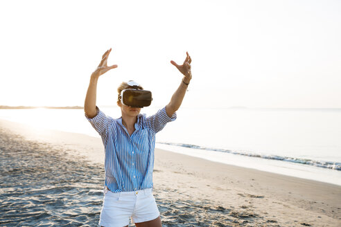 Blonde Frau macht eine Art von Yoga-Übungen an einem Strand in Thailand mit 3D-Virtual-Reality-Brille - HMEF00176