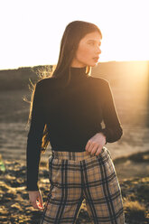 Porträt einer modischen Teenagerin mit schwarzem Pullover und karierter Hose bei Sonnenuntergang - ACPF00376