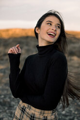 Portrait of laughing teenage girl wearing black pullover outdoors - ACPF00381