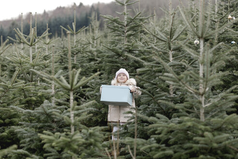 Mädchen trägt Geschenkbox auf einer Weihnachtsbaumplantage - KMKF00735