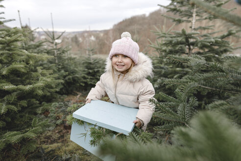 Glückliches Mädchen mit Geschenkbox auf einer Weihnachtsbaumplantage - KMKF00737