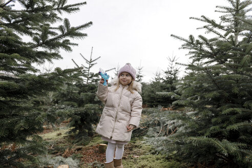 Glückliches Mädchen spielt mit Wasserpistole auf einer Weihnachtsbaumplantage - KMKF00740