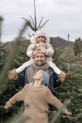 Porträt eines glücklichen Vaters mit zwei Kindern auf einer Weihnachtsbaumplantage - KMKF00743