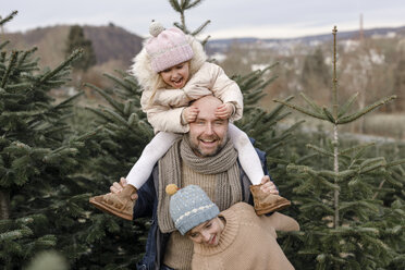 Porträt eines glücklichen Vaters mit zwei Kindern auf einer Weihnachtsbaumplantage - KMKF00745