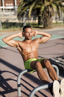Muskulöser Mann mit nacktem Oberkörper macht Sit-ups im Freien - MAUF02365