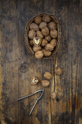 Wickerbasket of walnuts and nutcracker on wood - LVF07667