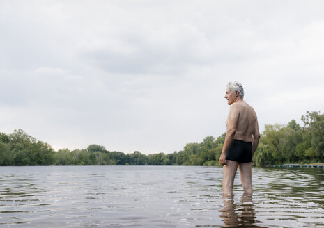 Älterer Mann steht in einem See - GUSF01790