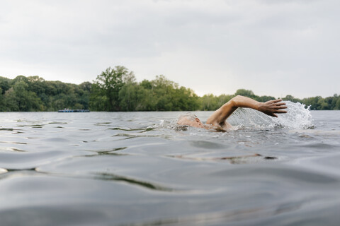 Älterer Mann schwimmt in einem See, lizenzfreies Stockfoto