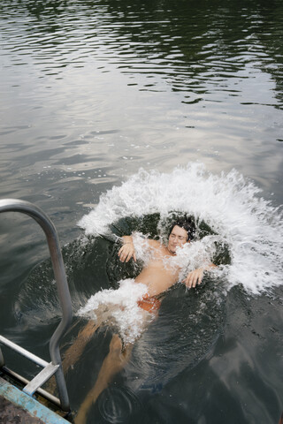 Mann springt vom Steg in einen See, lizenzfreies Stockfoto