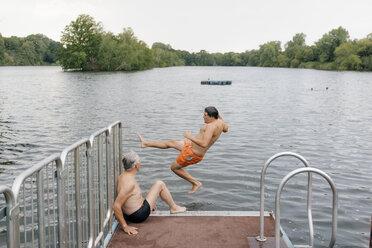 Man jumping from jetty into a lake - GUSF01796