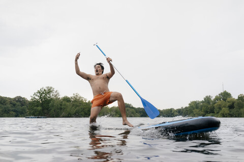 Mann fällt beim Selfie machen vom SUP-Board, lizenzfreies Stockfoto