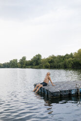 Senior man sitting on raft in a lake - GUSF01804